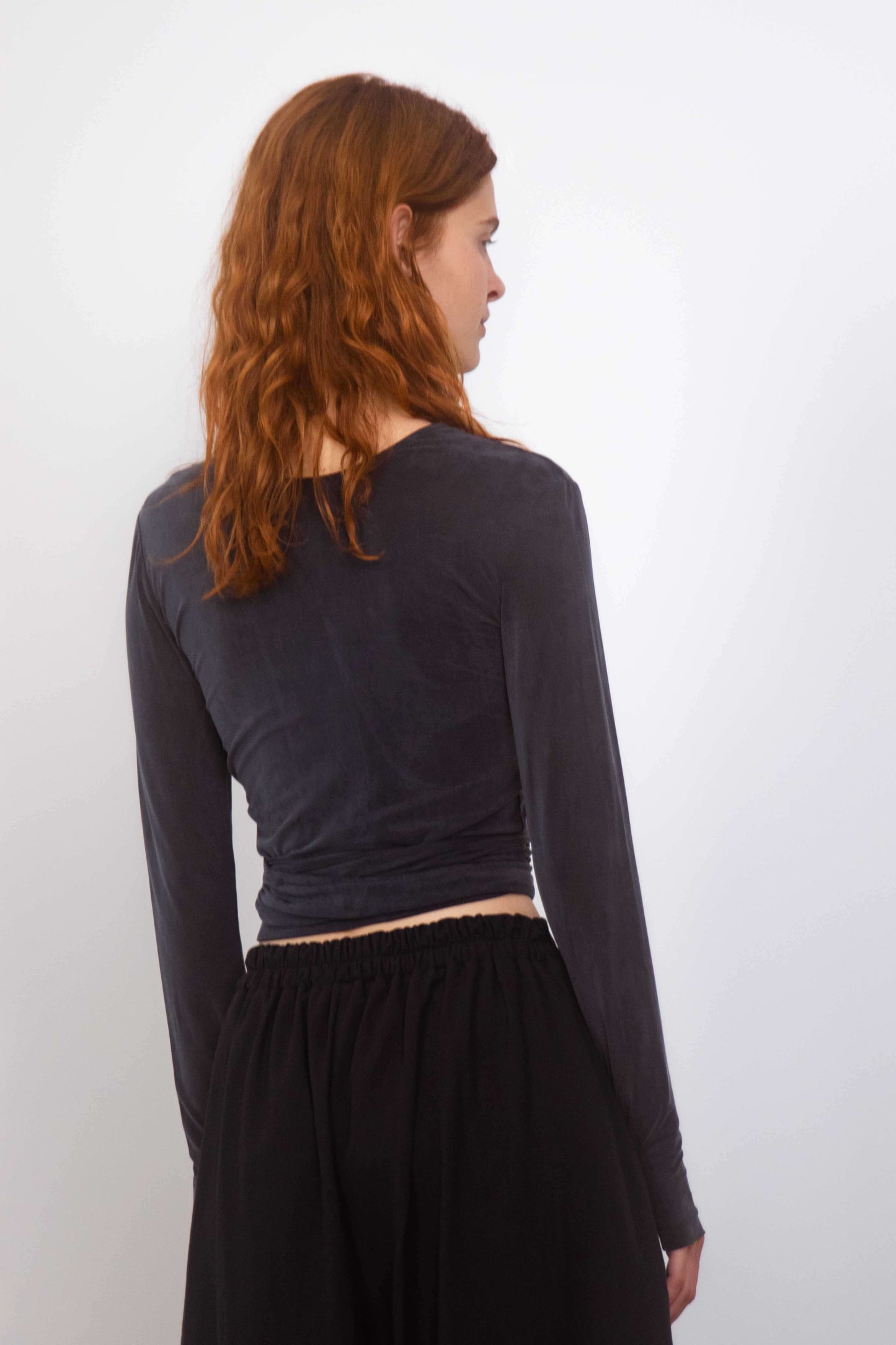 Back view of a model wearing the Cupro Multiway Wrap Top in Slate Black with long sleeves.