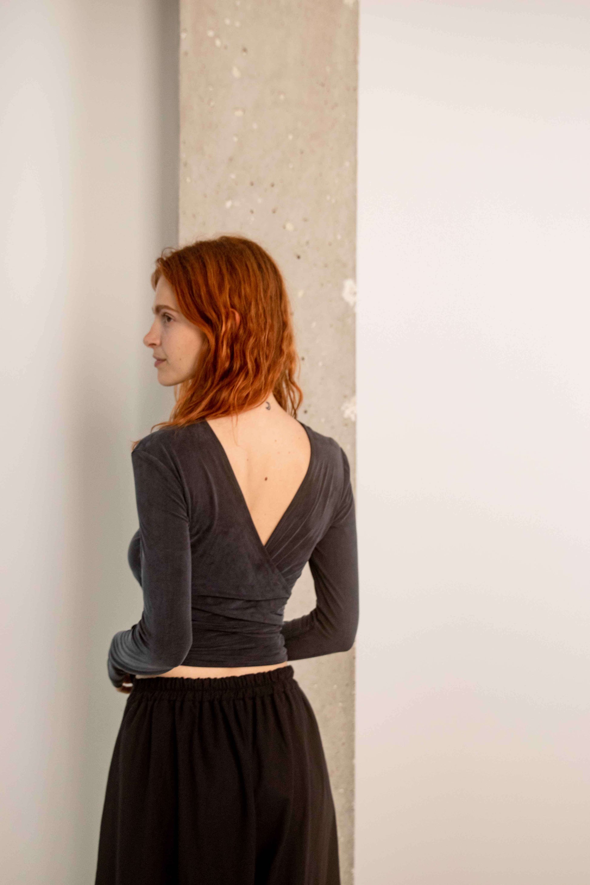 Model wearing a Cupro Multiway Wrap Top in Slate Black, showcasing the back design and versatile style.