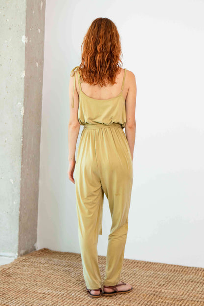 Woman wearing Cupro Slip Jumpsuit in Olive, showcasing the back view with a relaxed fit and slim cami straps.