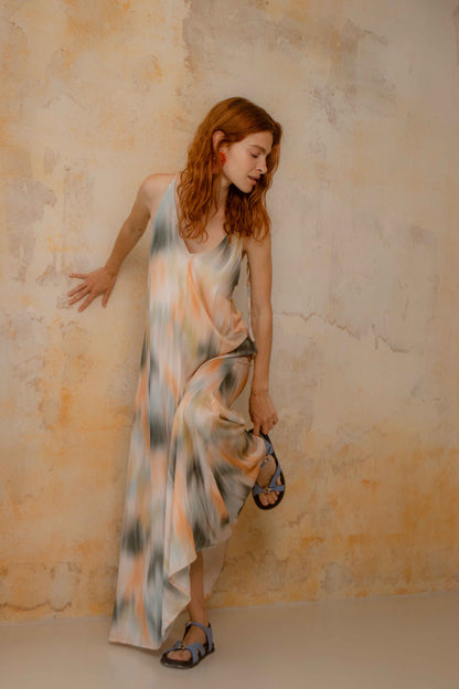 Model wearing a Printed Ecovero Viscose Maxi Dress, showcasing its fluid design and seasonal print against a textured wall.