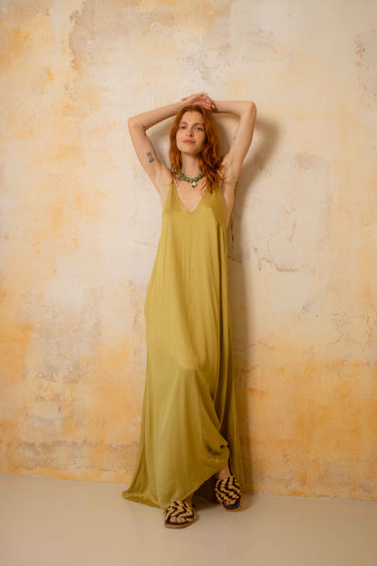 Model wears a Ecovero Maxi Dress, showcasing a lightweight, olive-colored design on a textured background.