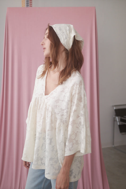 Model wearing a delicate ecru small lace scarf, highlighting its softness and organic cotton material, styled with a casual outfit.