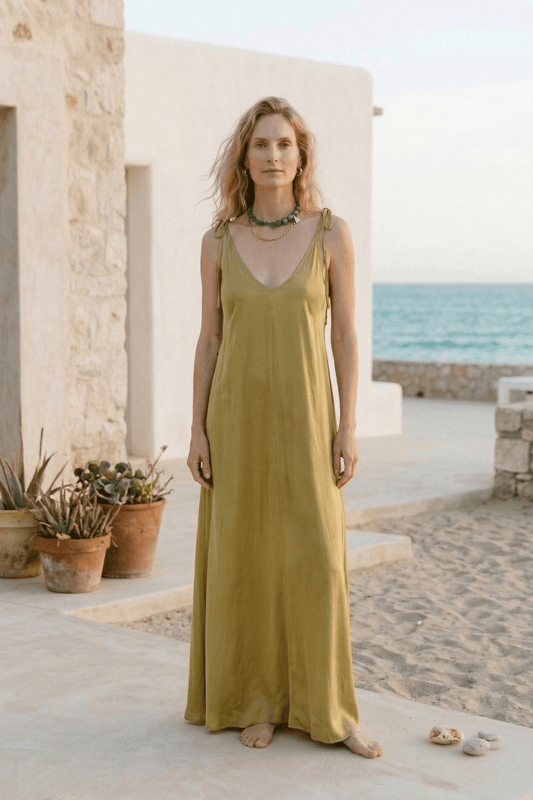 Ecovero Maxi Dress in Soft Olive, featuring adjustable straps and a flowing silhouette against a beach backdrop.