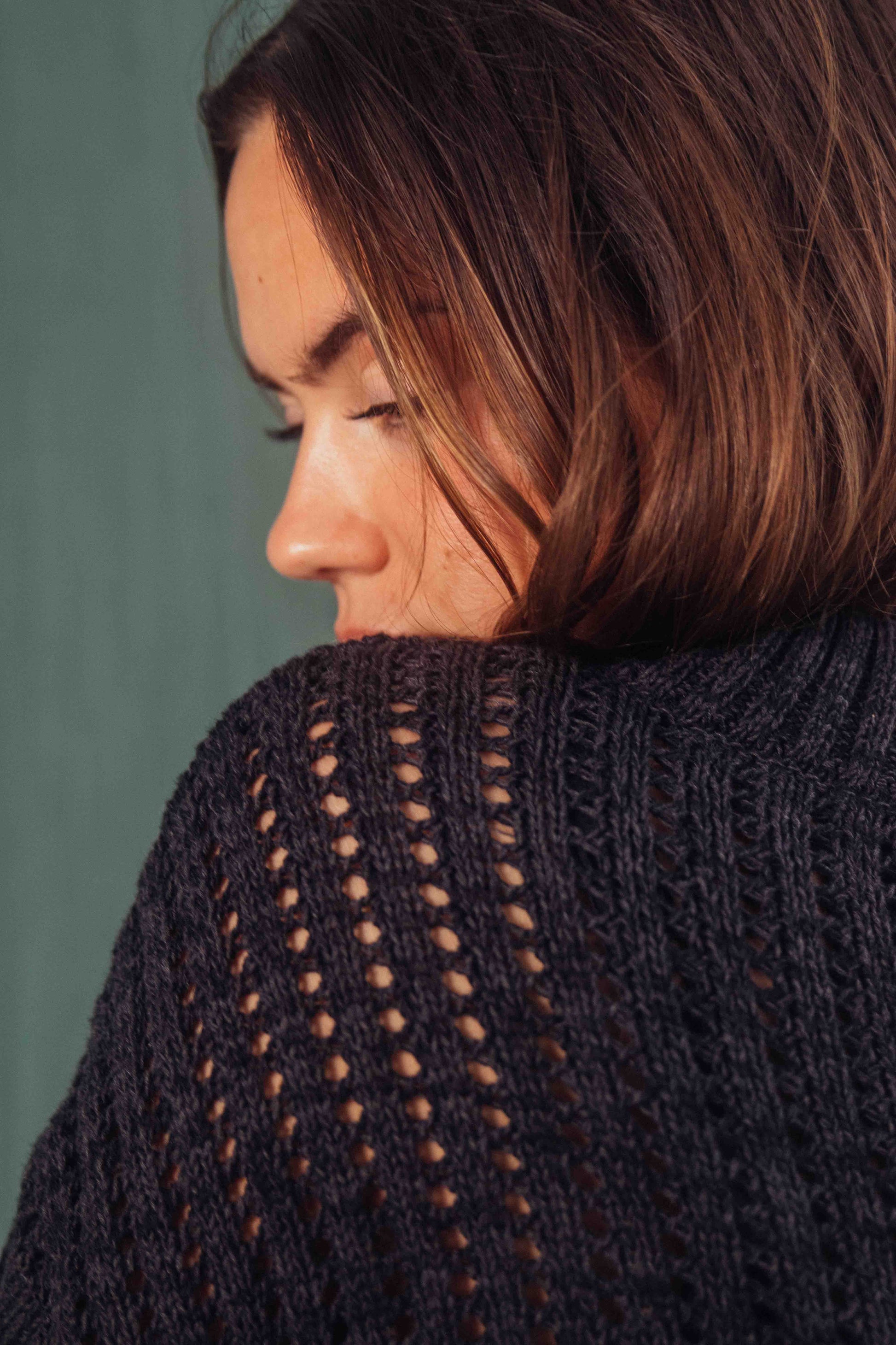 Model wearing MELANGE BLACK SWEATER made from 100% organic cotton yarn, featuring a crop and wide fit design.