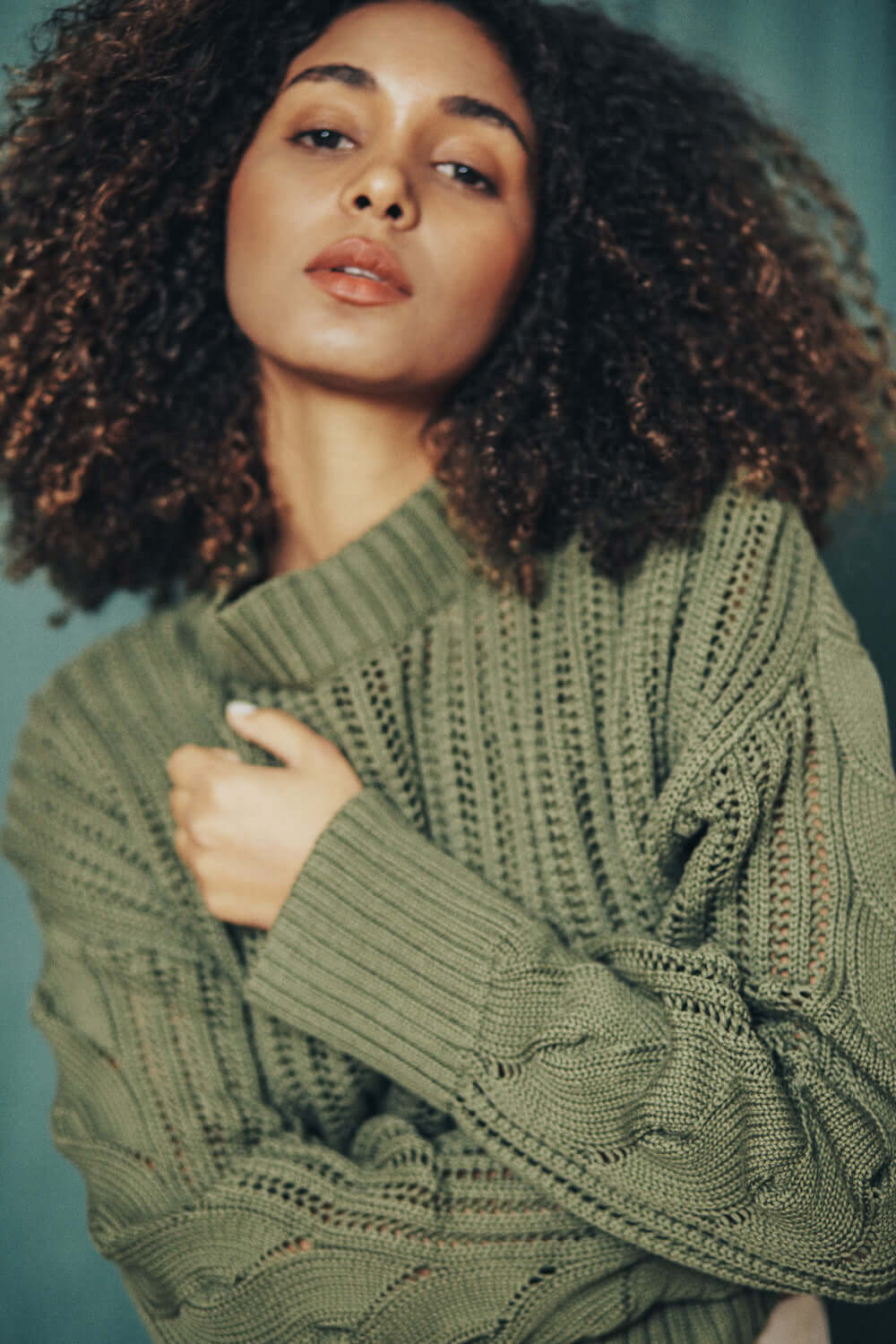 Woman in sage green sweater made from 100% organic cotton yarn, featuring a crop & wide fit design from Porto, Portugal.