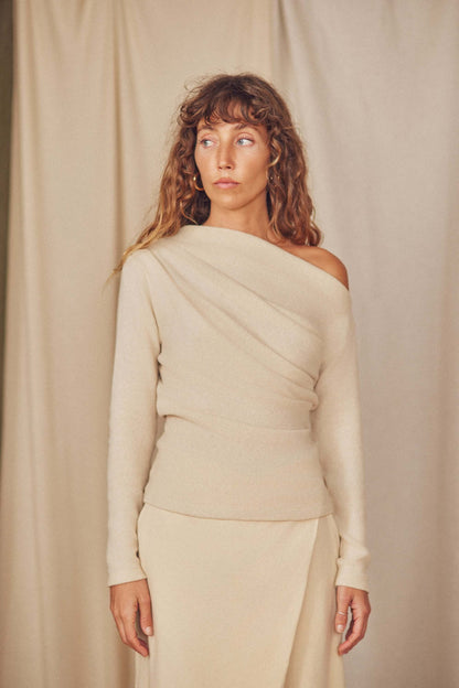 Model wearing a chic off-shoulder beige drape top, perfect for autumn layering with stylish draping and elegant fit.