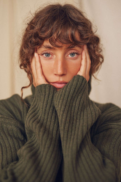 Model wearing khaki heavy knitted wool sweater with ribbed texture, showcasing style and comfort.