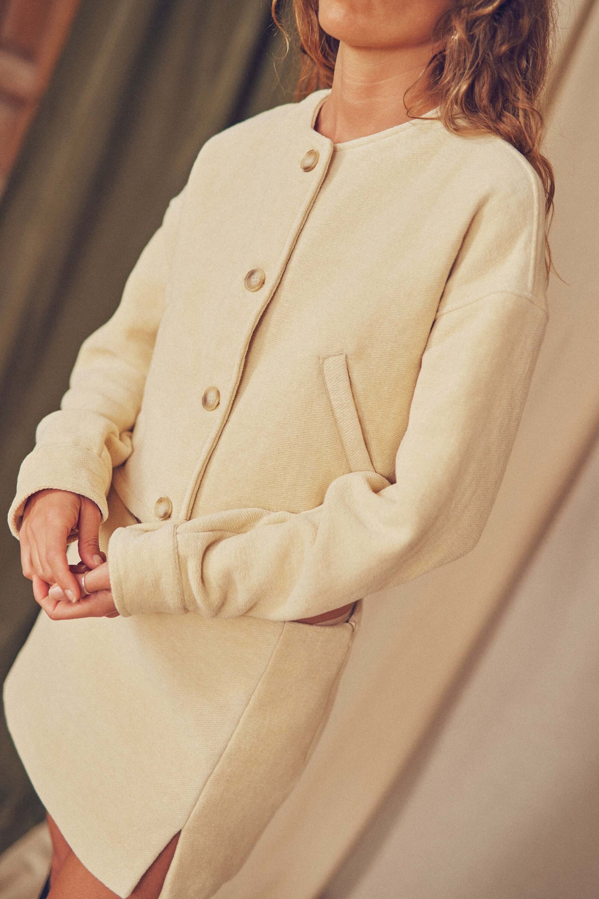 Model wearing Oat Organic Cotton Crop Jacket, showcasing bomber style and eco-friendly design with buttons.