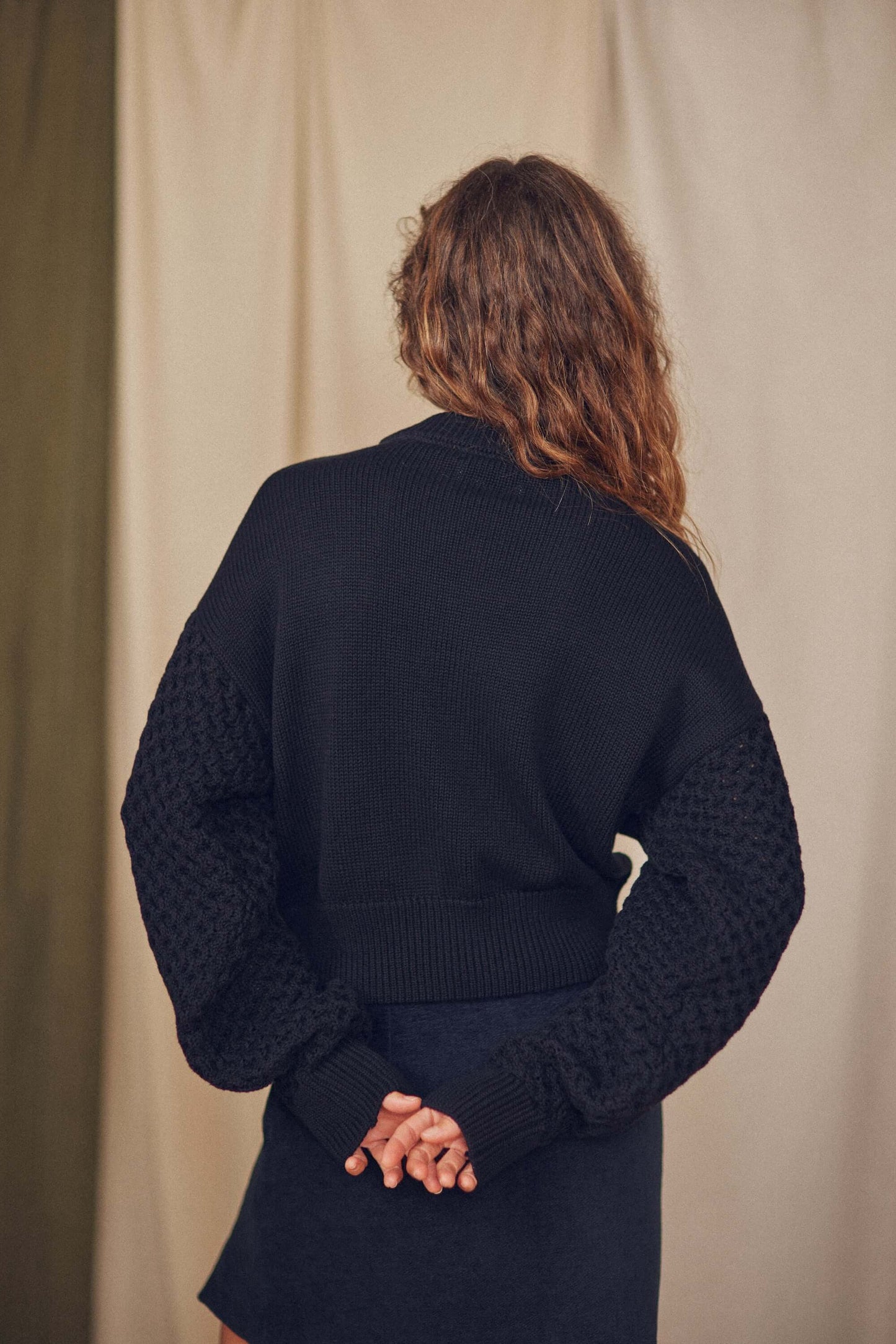 Back view of a Heavy Knit Black Vegan Sweater featuring elegant fantasy sleeves and a relaxed fit.
