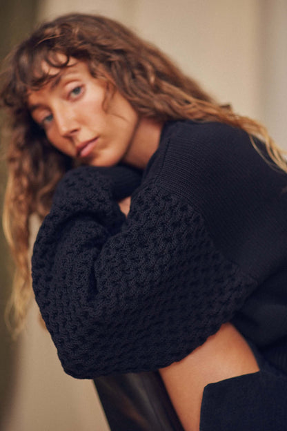 Model wearing a Heavy Knit Black Vegan Sweater with elegant fantasy sleeves, showcasing a relaxed fit and sustainable style.