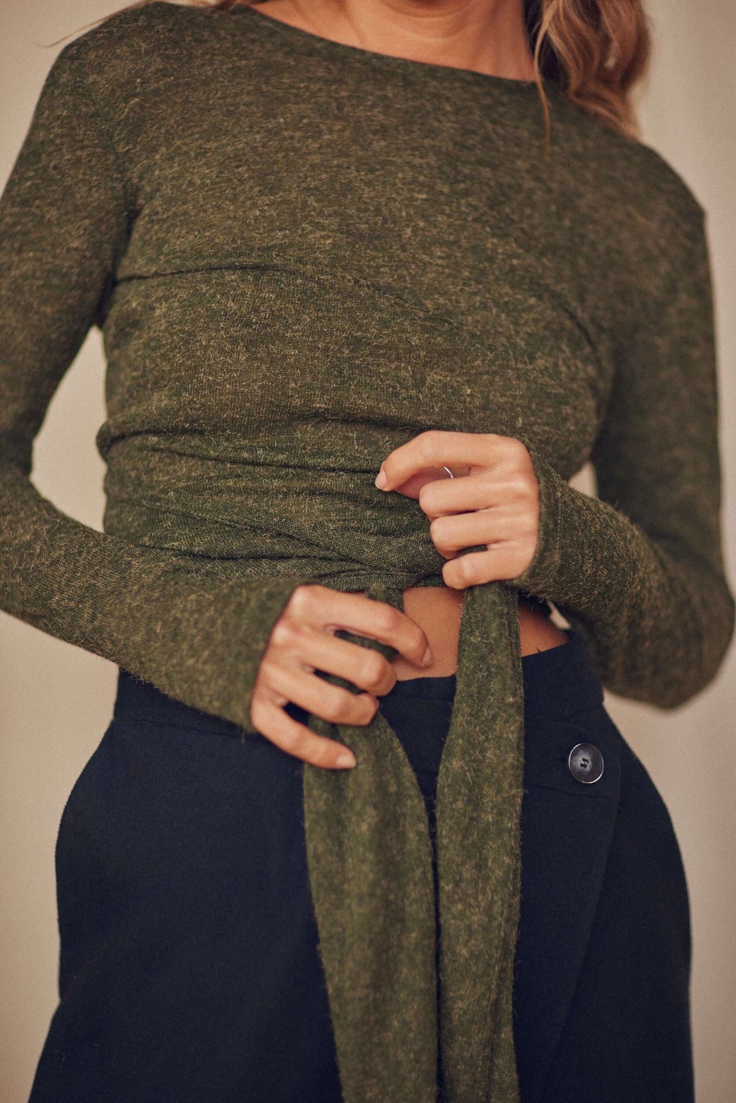 Model wearing khaki multiway recycled jersey wrap top with long sleeves and thumb holes, showcasing its versatile styling.