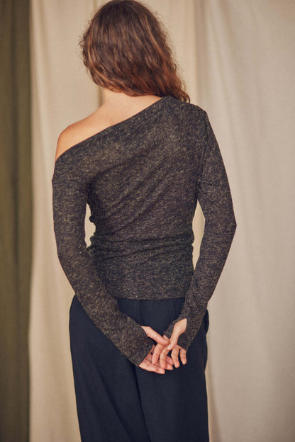 Back view of a woman wearing a chic black recycled jersey drape top with long sleeves and thumb holes.