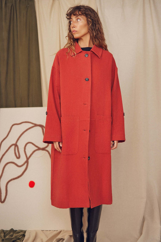 Woman wearing a rust wide coat.