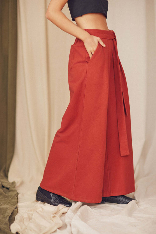 Rust organic cotton wide trousers featuring a voluminous silhouette and detachable belt, styled for autumn/winter.