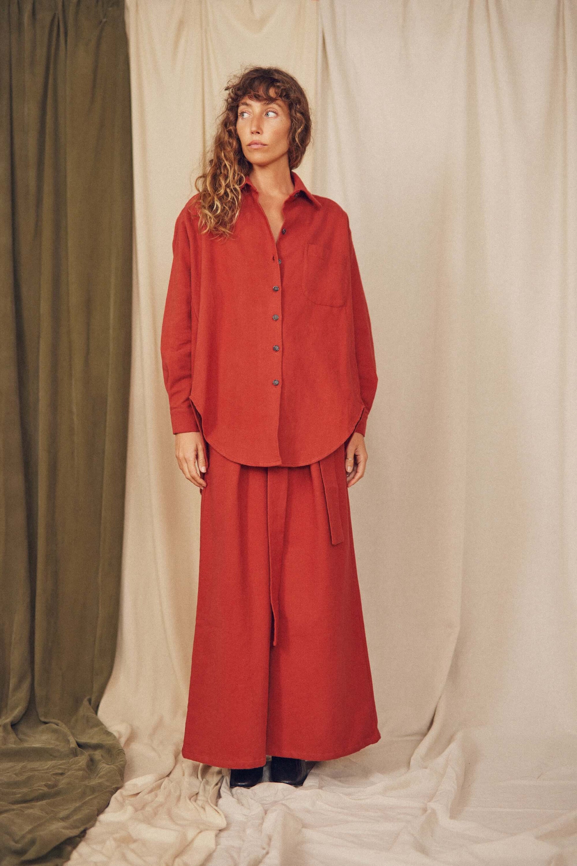Model wearing a rust organic cotton wide overshirt with matching pants against a soft, neutral backdrop.