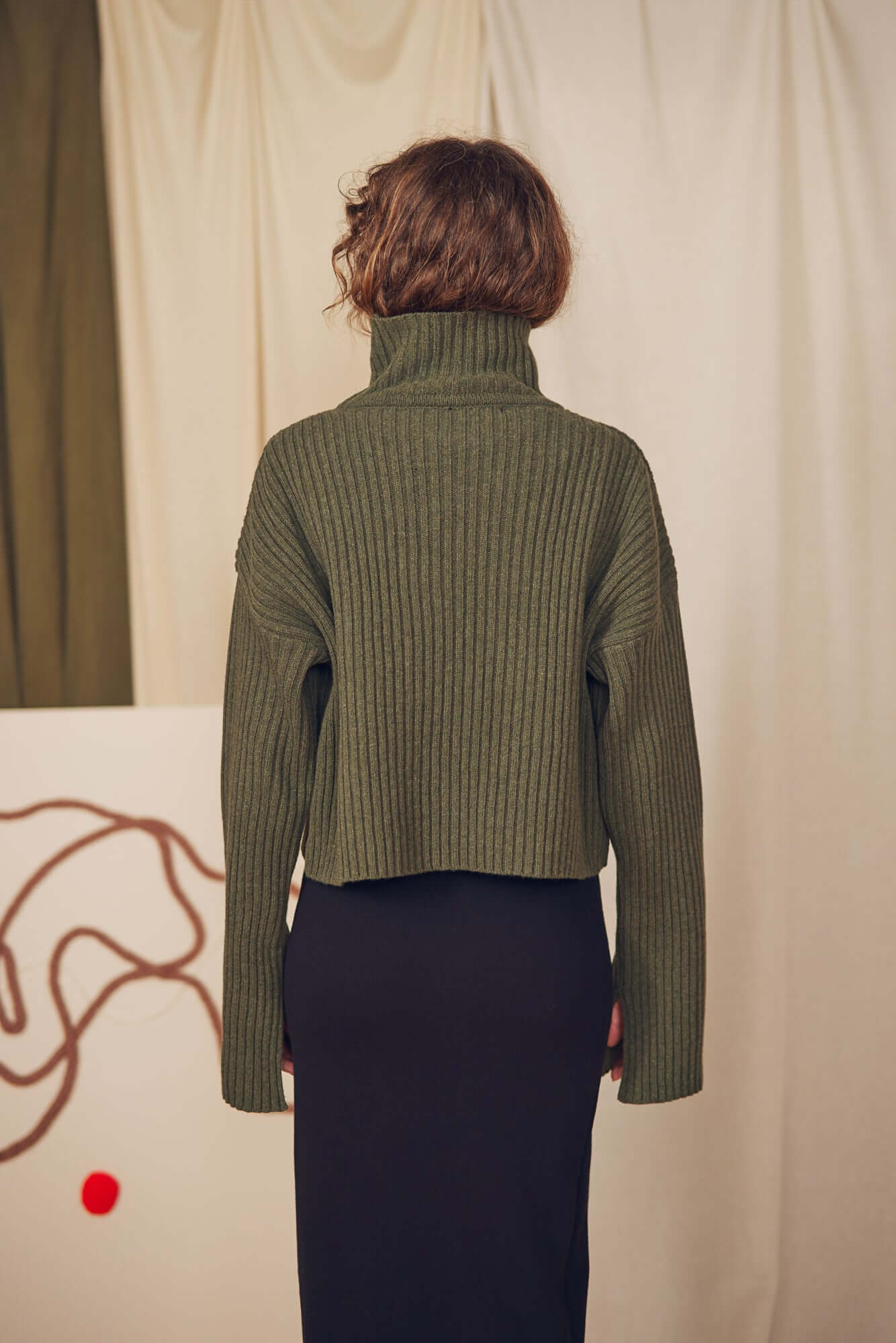Back view of a model wearing a Khaki Heavy Knitted Sweater with a high collar and ribbed texture.
