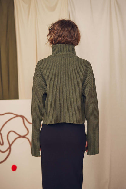 Back view of a model wearing a Khaki Heavy Knitted Sweater with a high collar and ribbed texture.