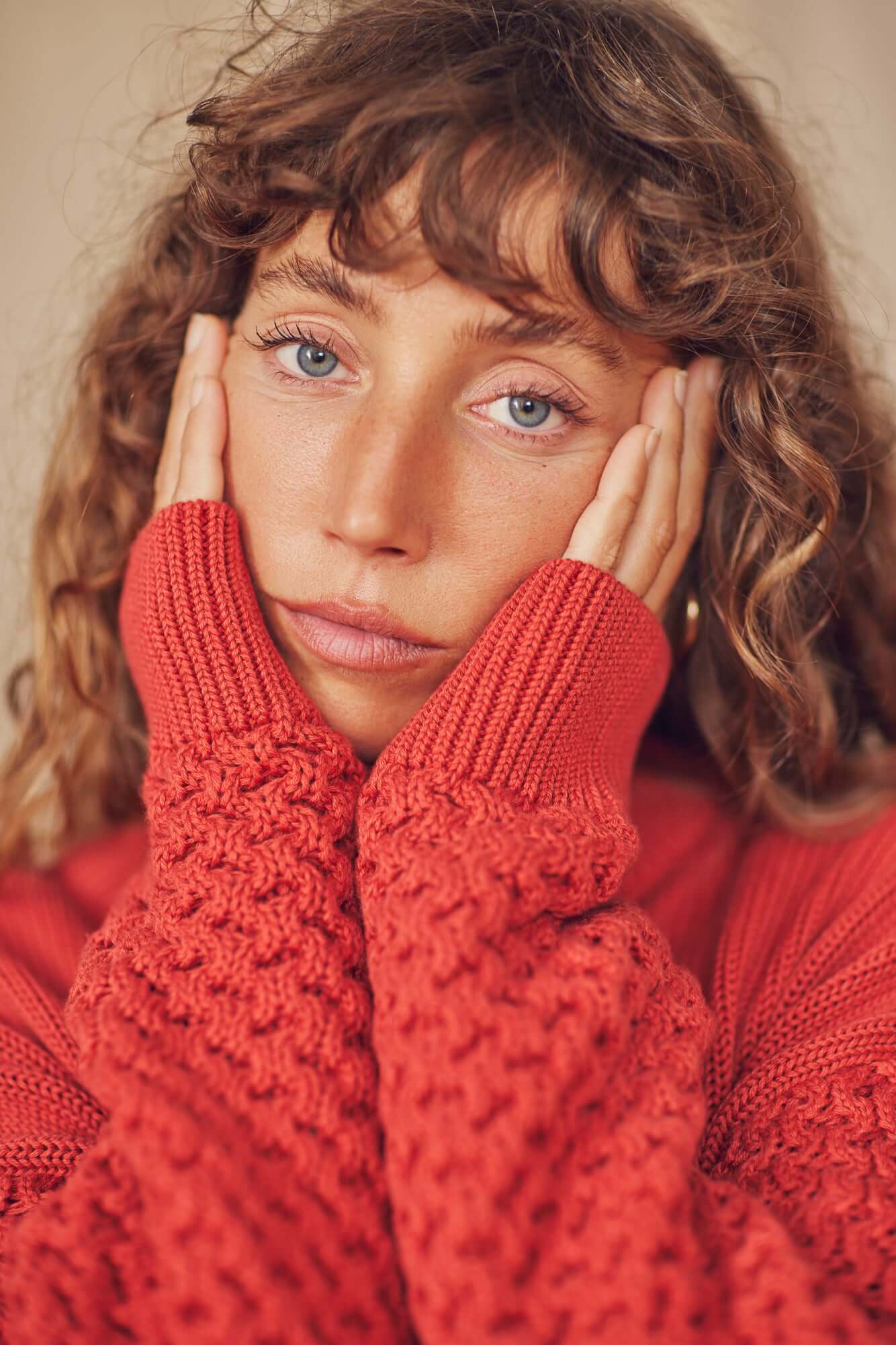 Close-up of a model wearing a Heavy Knit Rust Vegan Sweater with unique sleeve design.