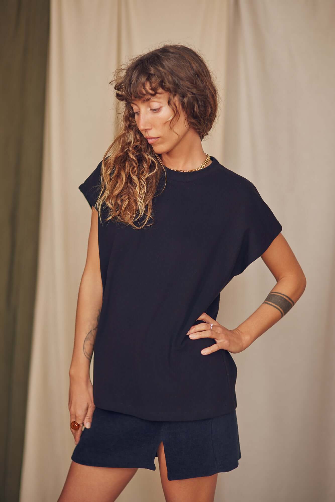 Woman wearing a black organic cotton mini skirt and matching top, showcasing a chic thigh split design.