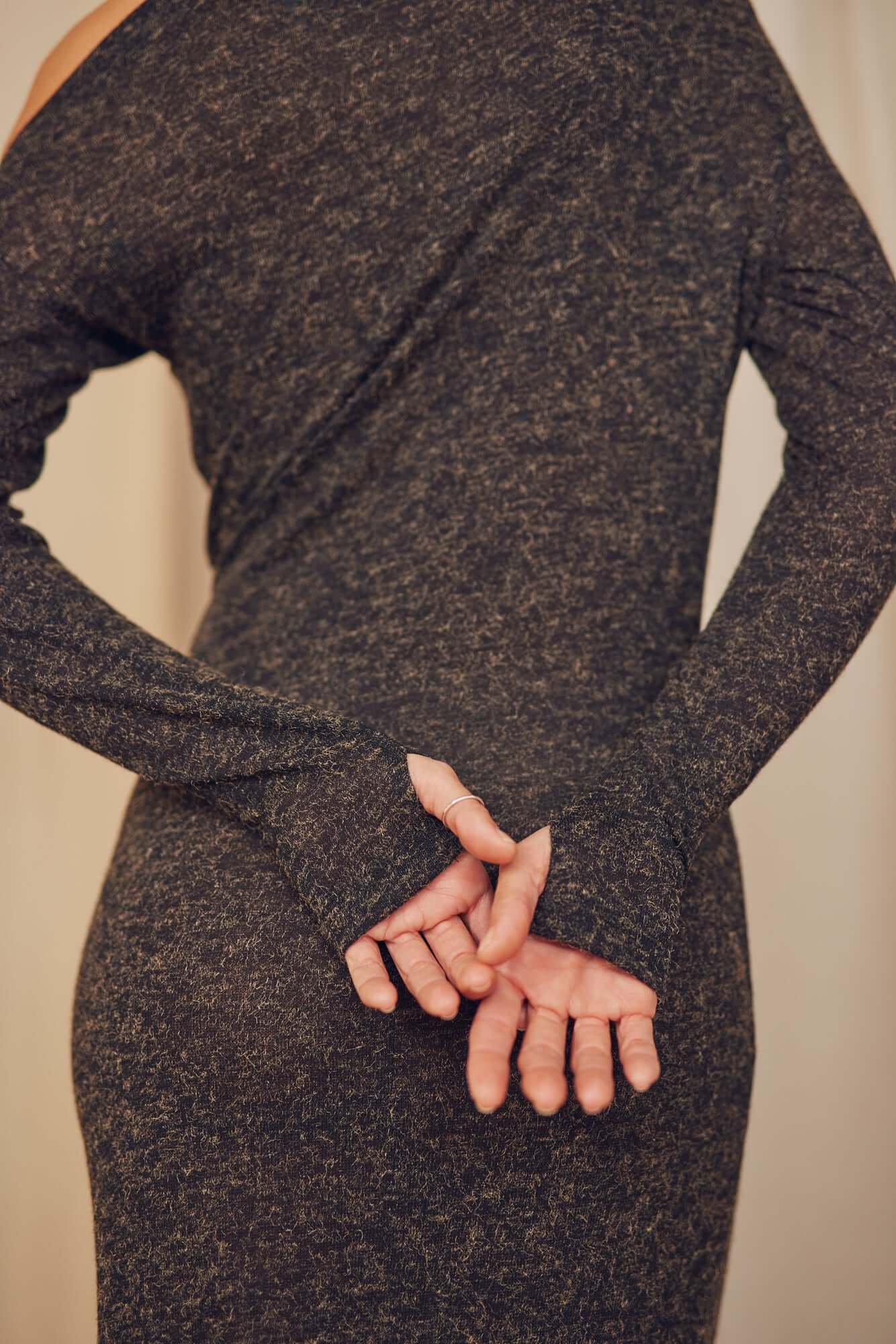 Back view of a model wearing a black recycled jersey drape dress with thumb holes, showcasing elegant style and comfort.