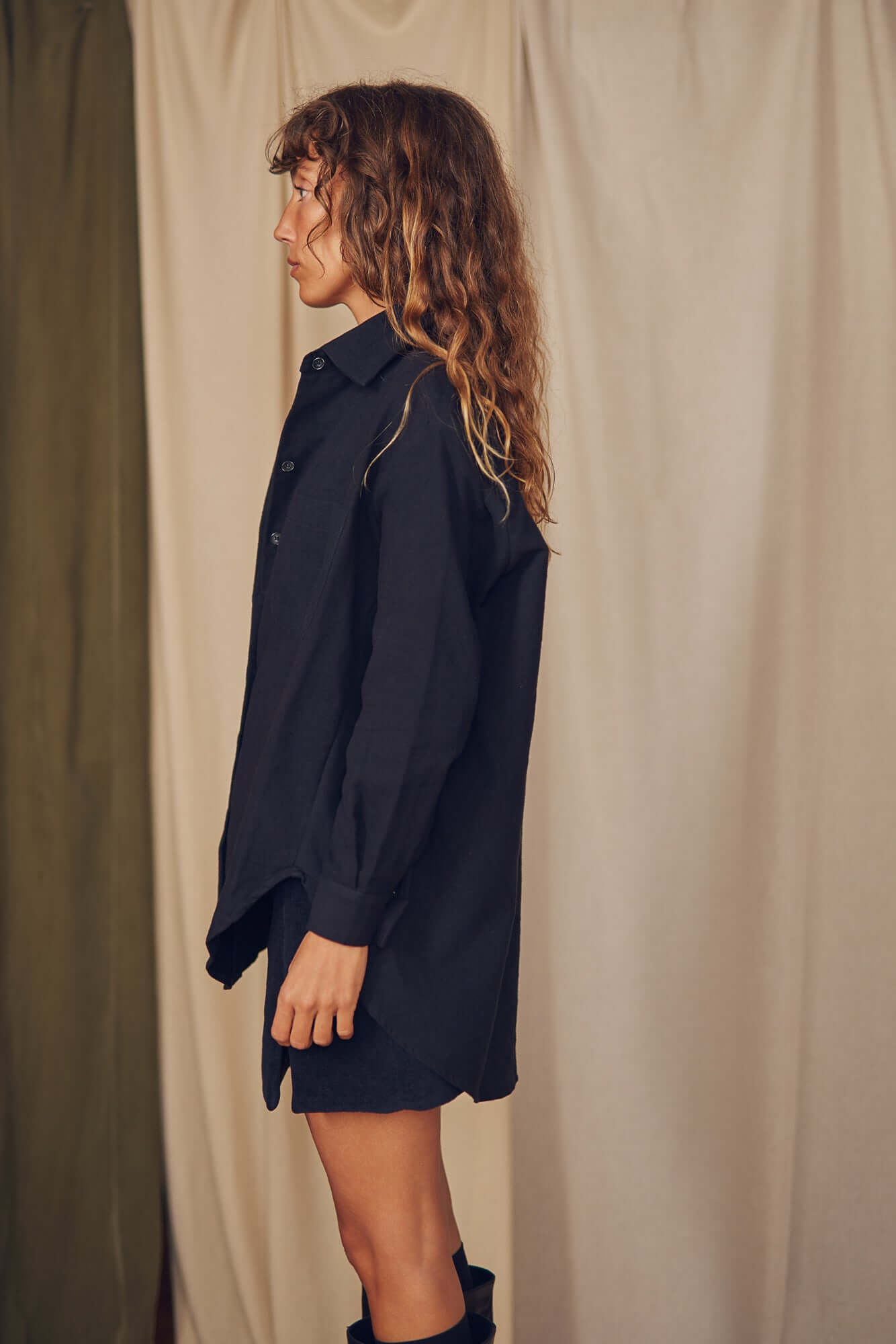 Model wearing a black organic cotton wide overshirt, styled in an oversized silhouette against a neutral backdrop.