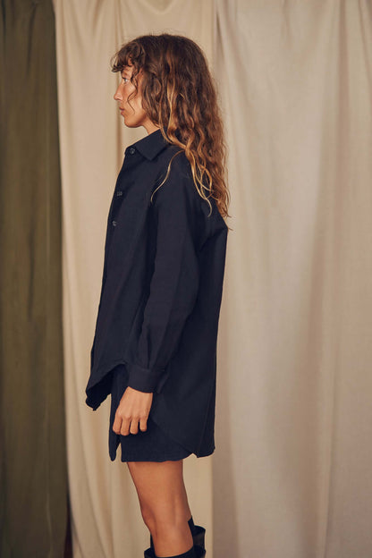 Model wearing a black organic cotton wide overshirt, styled in an oversized silhouette against a neutral backdrop.