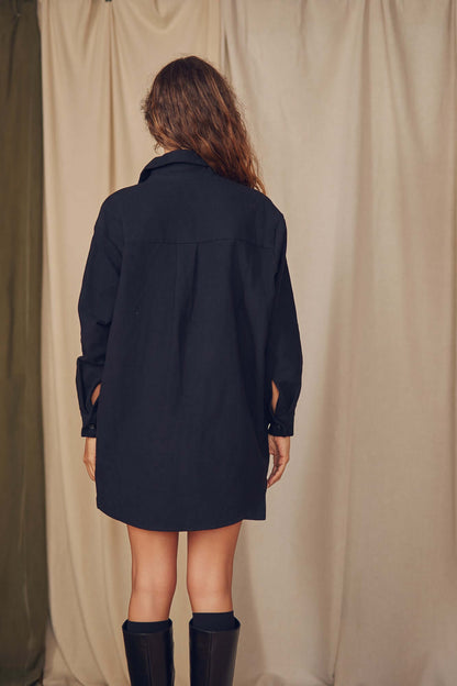 Back view of a model wearing a black organic cotton wide overshirt, showcasing its oversized silhouette.