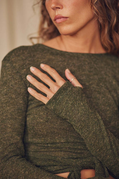 Close-up of a woman wearing a khaki recycled jersey wrap top with long sleeves and thumb holes.