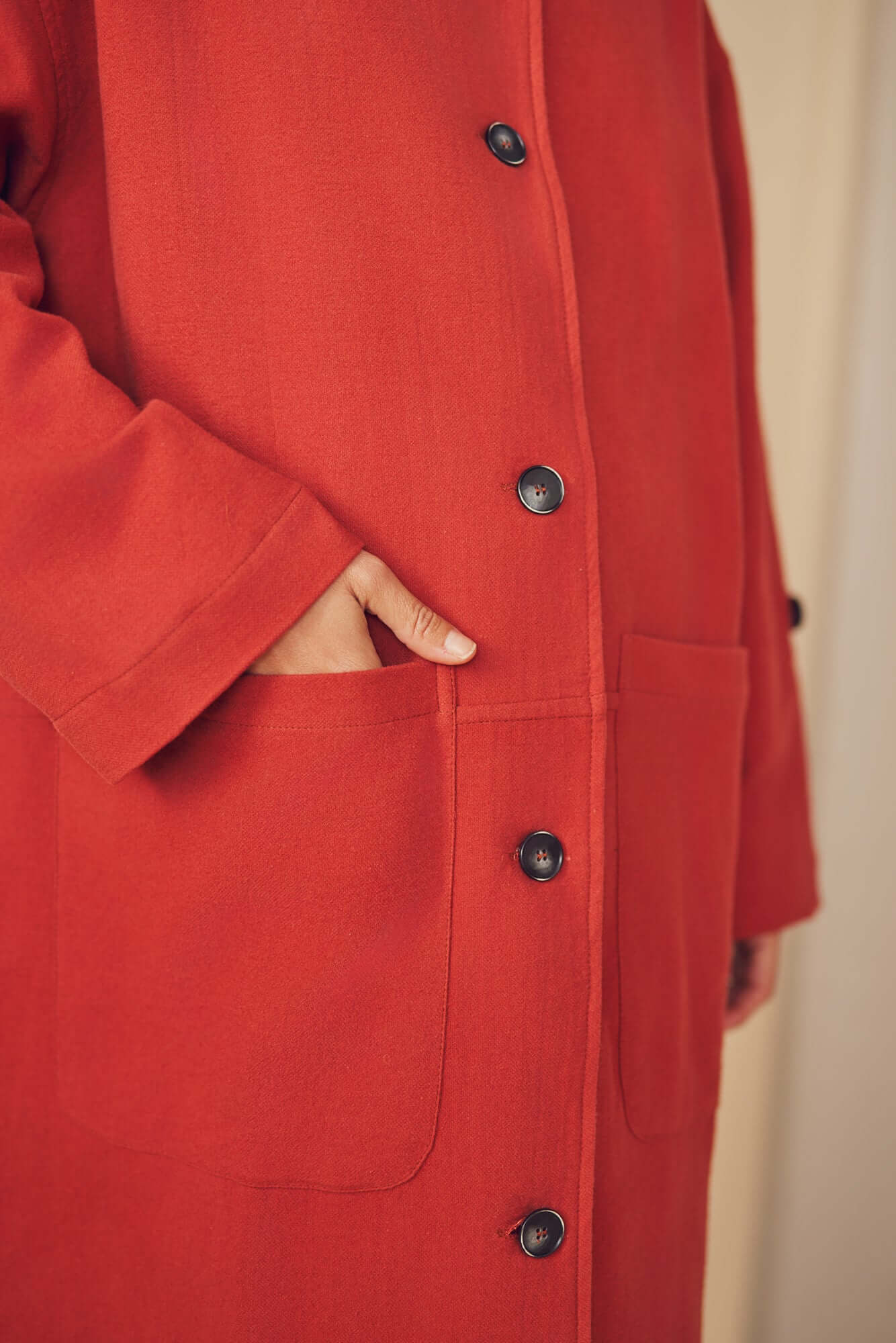 Woman wearing a rust wide coat.