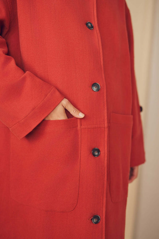 Woman wearing a rust wide coat.