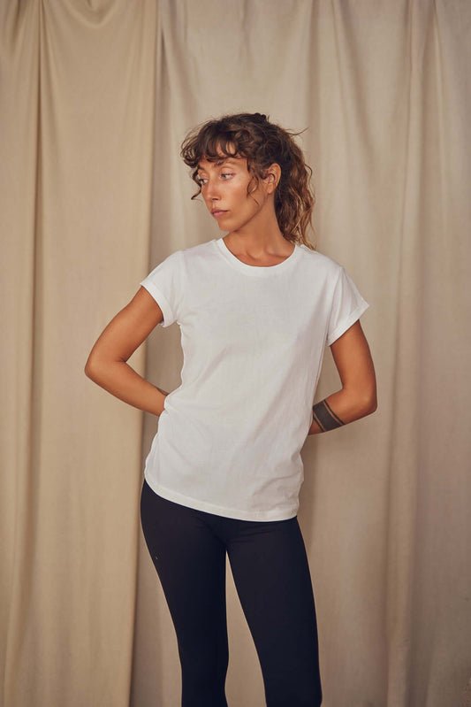 Short sleeve white classic tee made from 100% organic cotton, model wearing with black leggings against neutral backdrop.