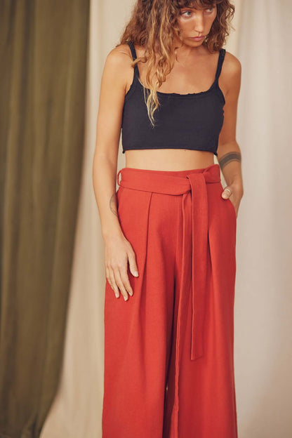  Woman styling rust organic cotton wide trousers with a black crop top.