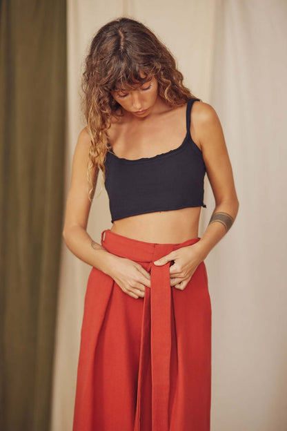 Woman styling rust organic cotton wide trousers with a black crop top.