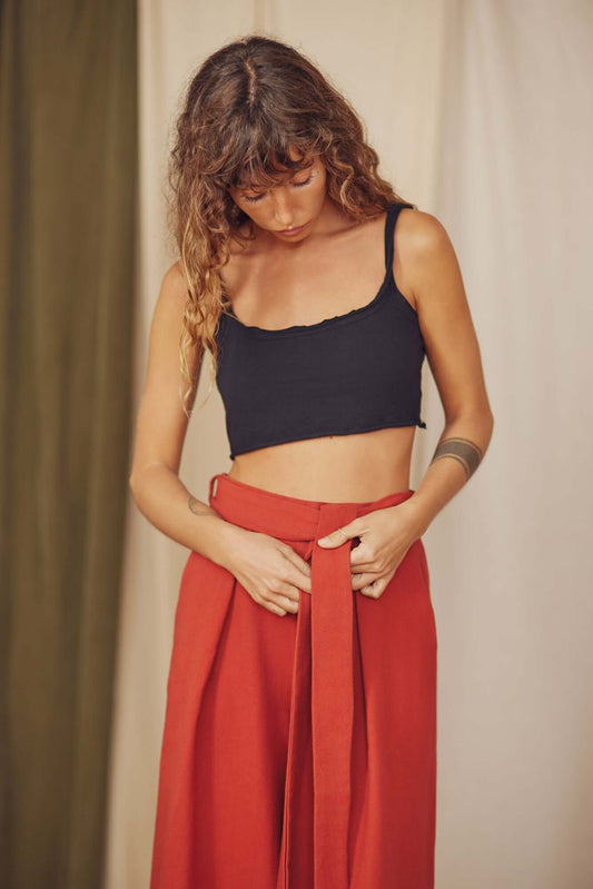 Woman styling rust organic cotton wide trousers with a black crop top.
