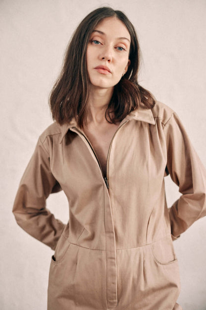 Woman wearing taupe denim boilersuit made from organic cotton, showcasing a timeless and versatile jumpsuit style.