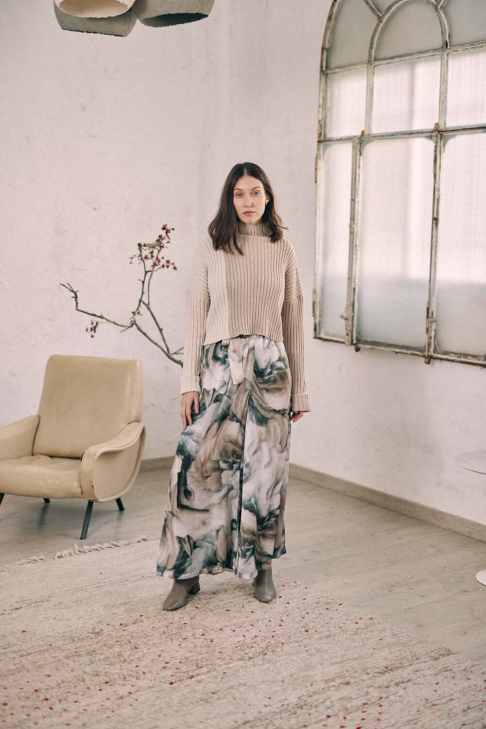 Woman wearing printed wide trousers with separate belt, made from 100% Ecovero viscose. Cozy autumn fashion in neutral tones.