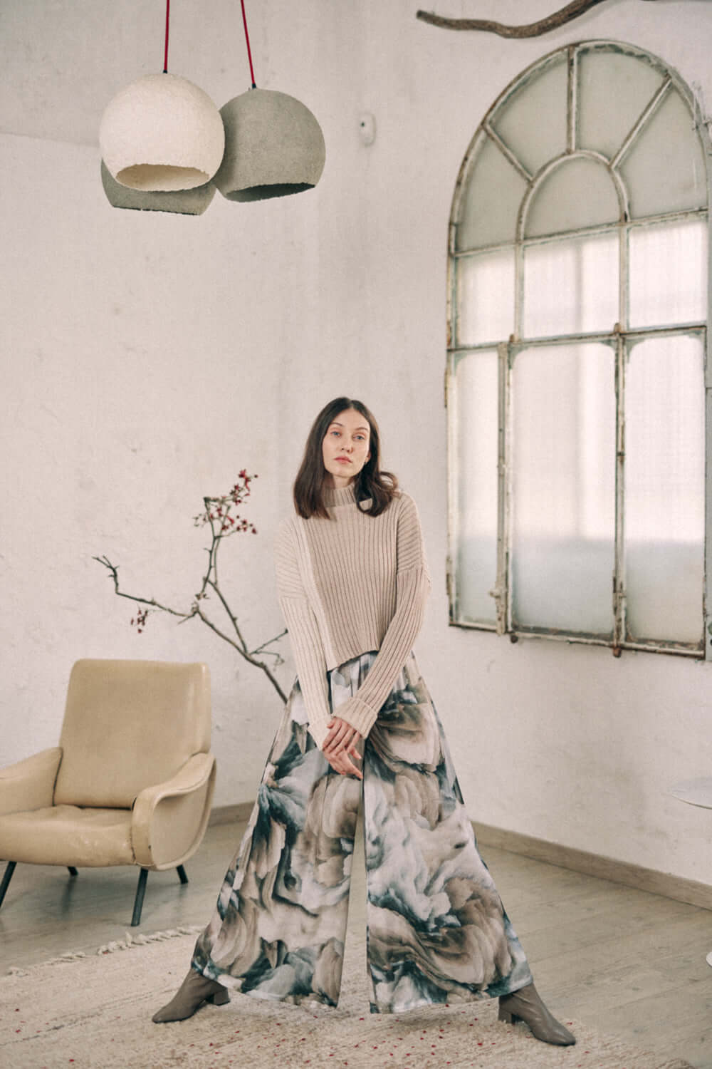 Woman modeling printed wide trousers in Ecovero viscose, showcasing new autumn print with separate belt, standing in stylish room.