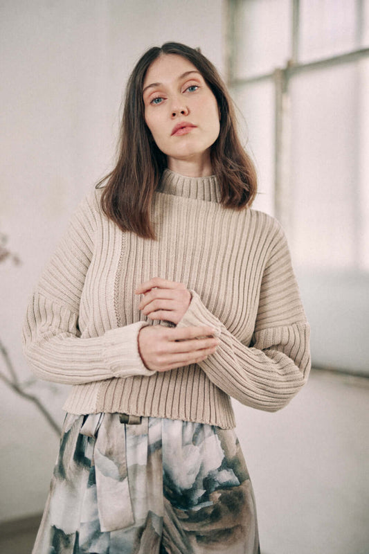 Woman wearing a Bicolor Beige Sweater made from organic cotton with a high neck, showcasing a cozy, timeless design in beige tones.