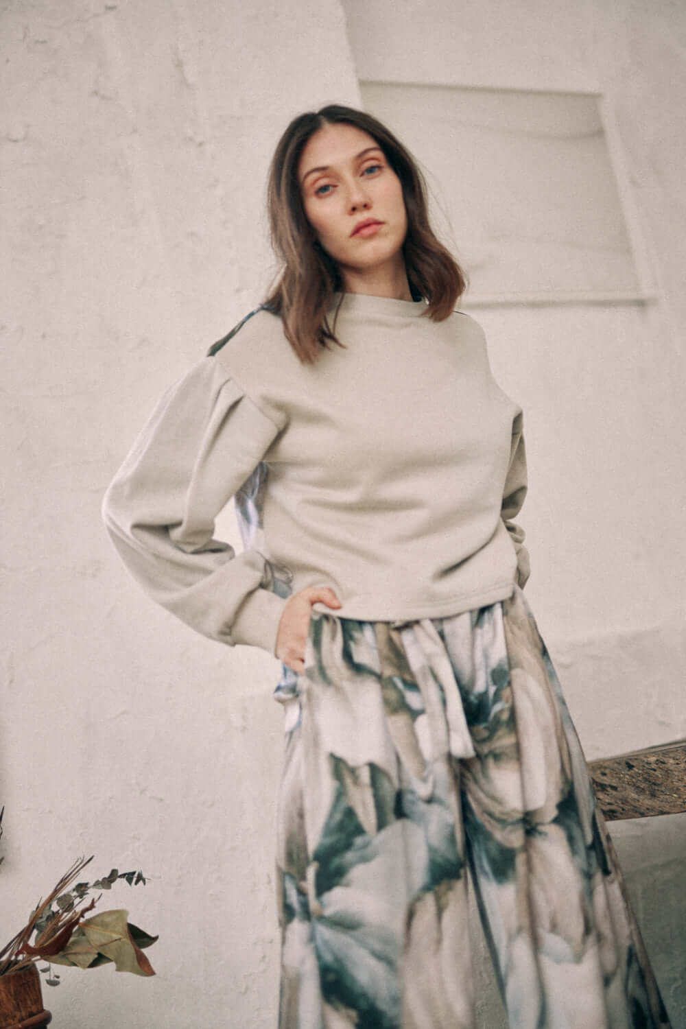 Woman wearing a printed reversible sweatshirt with floral pants, versatile fashion, eco-friendly material, stylish outfit in neutral tones