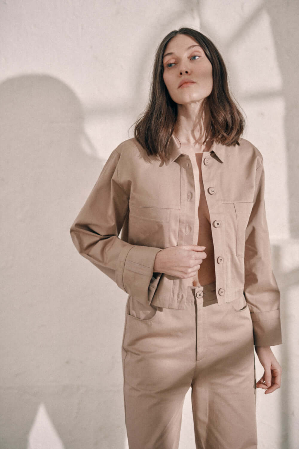 Model wearing taupe denim jacket with branded COSSAC buttons and turned-up sleeves, made from 100% organic cotton woven sarga from Porto