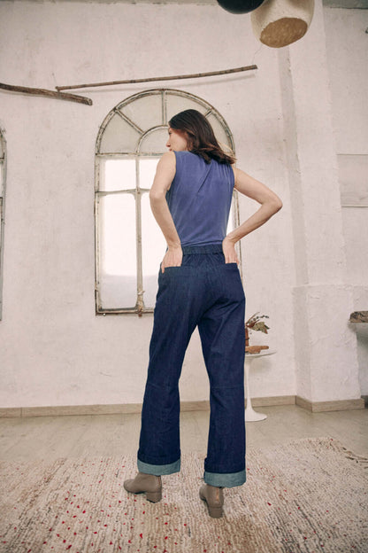 Model wearing navy denim trousers with turned-up ankles, back view, 100% organic cotton woven denim from Porto.