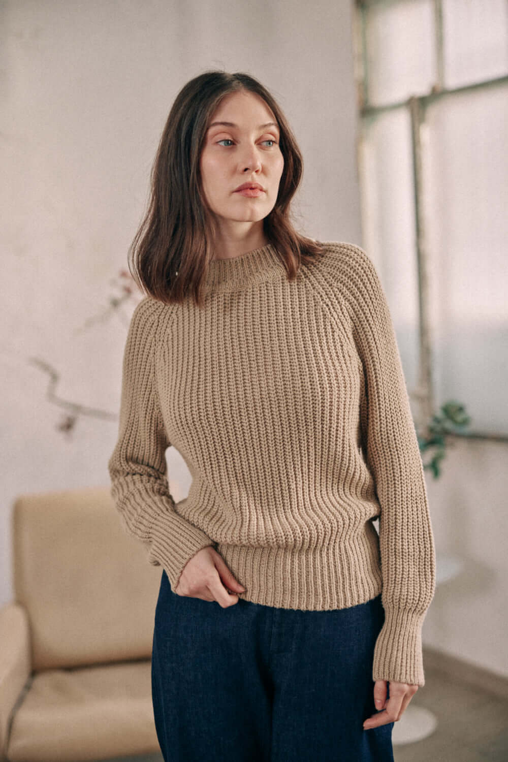 Woman wearing taupe sweater made of organic cotton, showcasing the online exclusive sustainable fashion piece.