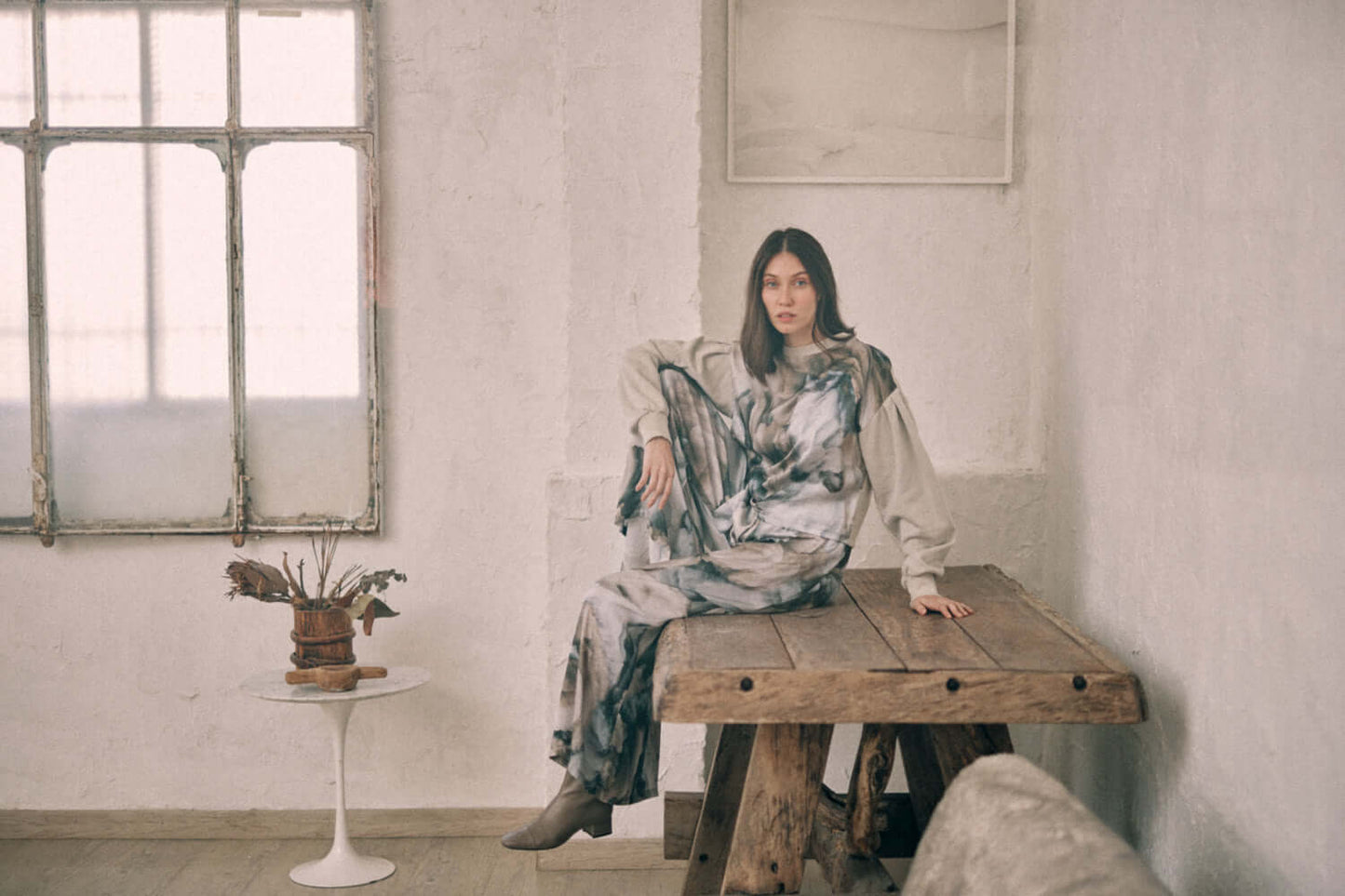 Woman in printed reversible sweatshirt seated in a rustic room displaying versatile fashion style.