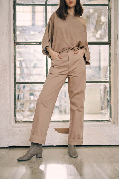 Woman wearing taupe denim trousers made of 100% organic cotton with turned ankles, showcasing modern design details and COSSAC buttons.