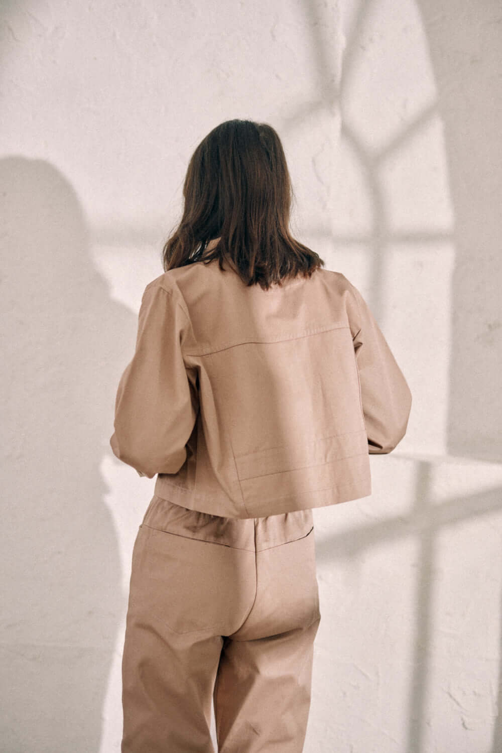 Back view of model wearing taupe denim jacket and pants made from 100% organic cotton woven sarga from Porto, Portugal.