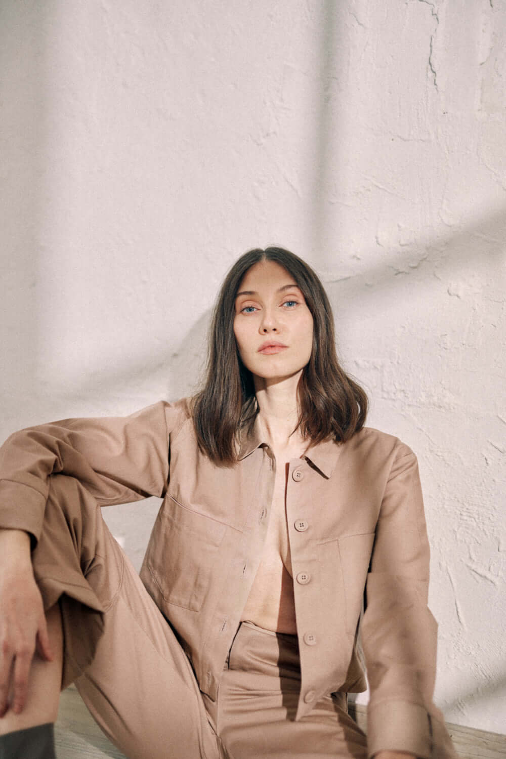 Woman wearing taupe denim jacket with turned sleeves and matching pants, made from organic cotton, featuring COSSAC buttons.