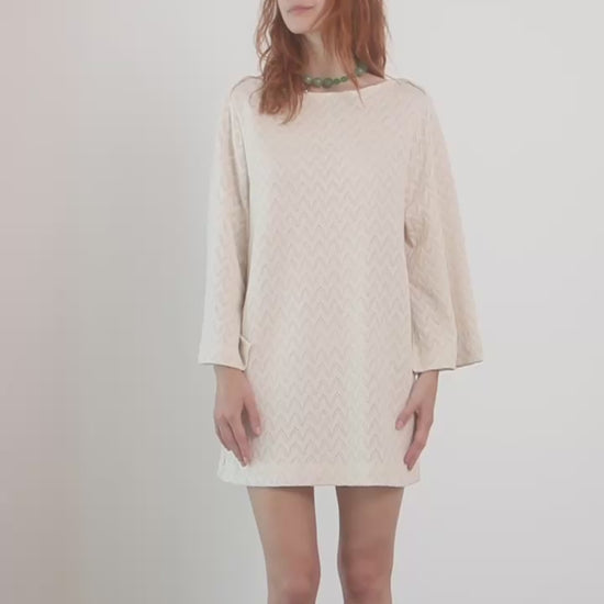Model wearing an Organic Cotton Crochet Mini Dress with flared sleeves in ecru, showcasing a playful summer style.