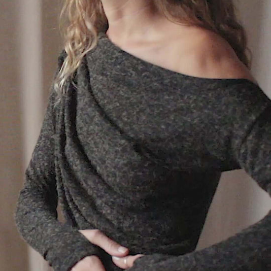 Model wearing a black recycled jersey drape dress with an off-shoulder neckline and thumb holes, showcasing autumn style.