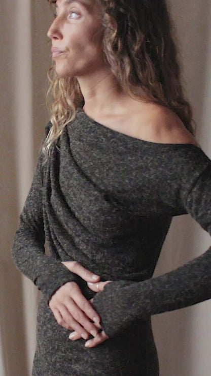 Model wearing a black recycled jersey drape dress with an off-shoulder neckline and thumb holes, showcasing autumn style.
