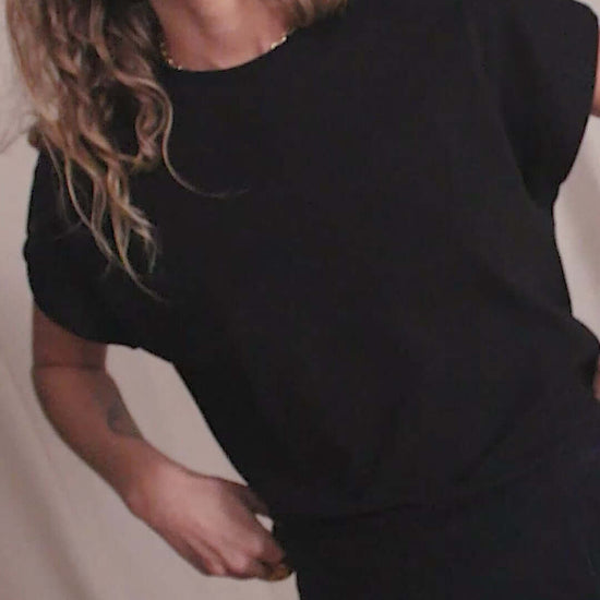 Woman wearing a black organic cotton basic tee with short cap sleeves, showcasing minimalist style and sustainability.